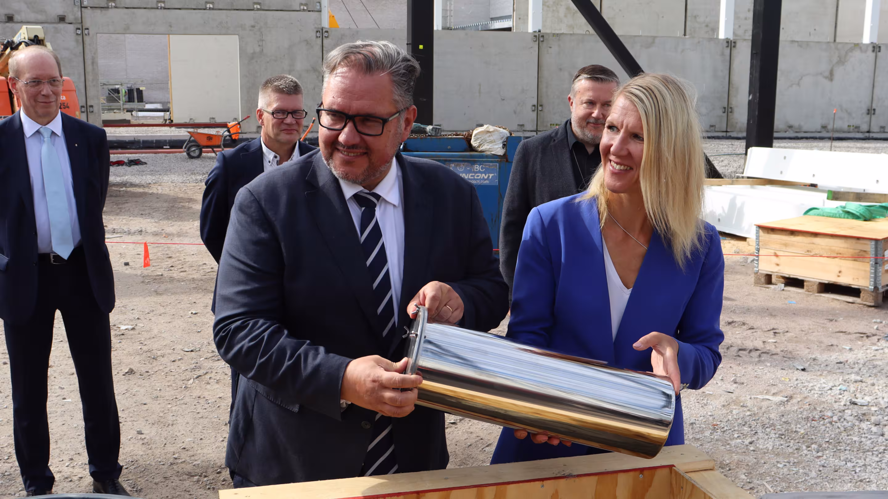 Suomen ympäristö- ja ilmastoministeri Sari Multala ja opetus- ja kulttuuriministeriön ylijohtaja Juha Rintamäki asettavat aikakapselin peruskiveen muurattavaksi. 